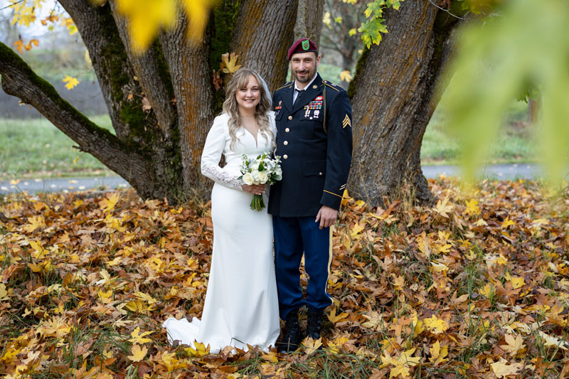 Bride and groom in military uniform under maple tree for country wedding