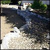 Portland drainage and dry creekbed combination routed around water and rock in landscape